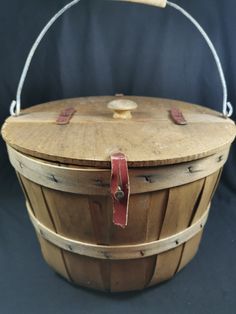 an old wooden basket with leather straps on the handle and bottom, sitting on a black background