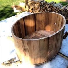 a large wooden tub sitting on top of a white tile floor next to firewood