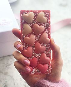 a person holding up a phone case with hearts on it