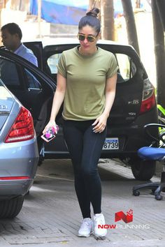 a woman in black leggings and a green shirt stepping out of a car