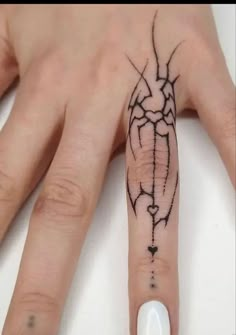 a person's hand with a tattoo on it and a white manicured nail