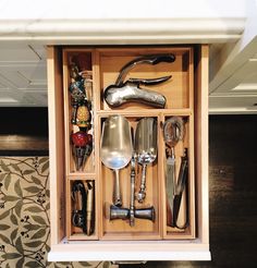 an open drawer with utensils and spoons in it on top of a table