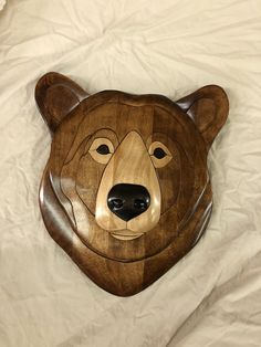 a wooden bear head laying on top of a white sheet