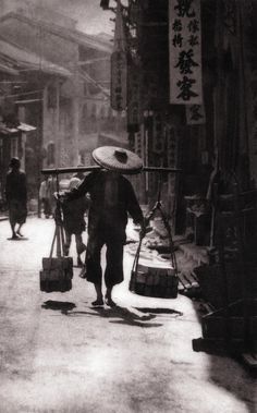 an old black and white photo of people walking down the street