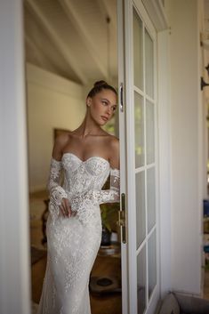 a woman in a white wedding dress is standing by the door with her hands on her hips