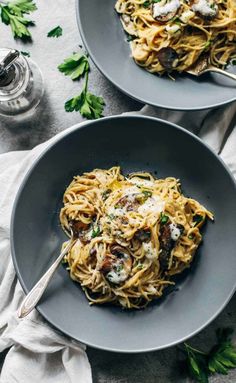 two plates of spaghetti with mushrooms and parsley