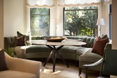 a living room filled with furniture and a table in front of a large round window