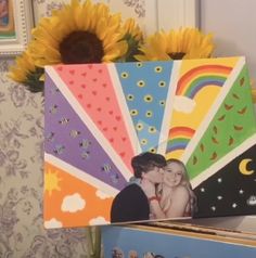 a couple kissing each other in front of sunflowers and pictures on the wall