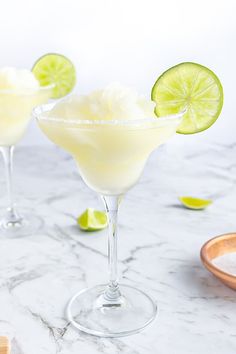 two margarita cocktails with lime slices on the rim