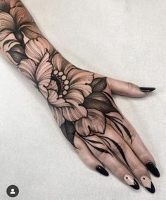 a woman's hand with black and white flowers on it, which is painted