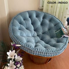 a blue chair sitting on top of a wooden floor next to a vase with flowers