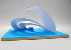 a sculpture made out of paper on top of a blue board