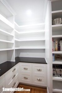 an empty pantry with white cabinets and black counter tops