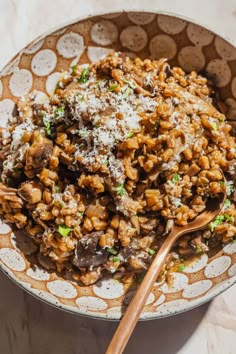 a bowl filled with meat and rice covered in parmesan cheese on top of a table