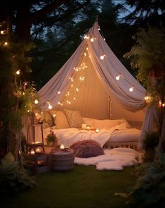 a canopy bed with lights hanging from it's sides and pillows on the ground