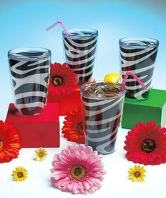 several glasses with different designs and flowers around them