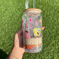 a hand holding a cup with spongebob characters on it and sprinkles