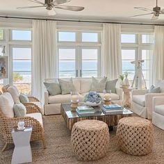 a living room with wicker furniture and large windows overlooking the beach in front of it