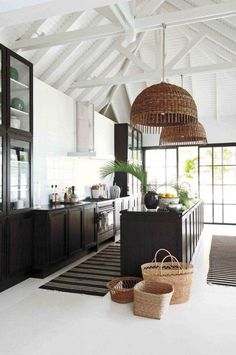 a kitchen with white walls and wooden cabinets, black counter tops and baskets on the floor