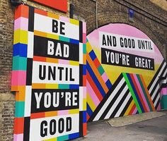 two large colorful signs on the side of a building that says be bad until you're good