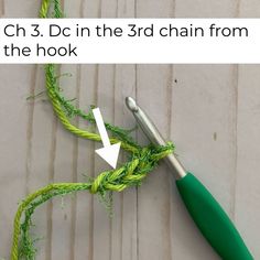 the crochet hook is being used to make a green rope with an arrow