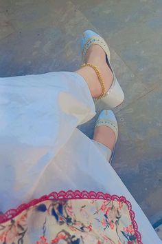 a woman's feet in high heels and white dress