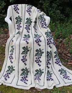 a white crocheted blanket sitting on top of a grass covered field