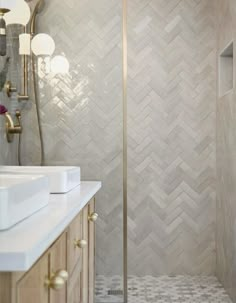 a bathroom with a walk in shower next to a white sink and wooden cabinetry