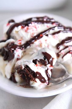 two scoops of ice cream on a white plate with chocolate and candy canes