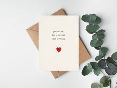 a card with a heart on it next to some leaves