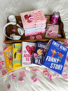 a wooden box filled with books and headphones on top of a white bed covered in pink flowers