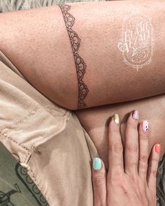 a woman's legs with tattoos on them and her hand resting on the leg