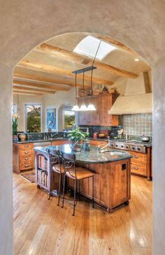 a large kitchen with an island in the center and wooden cabinets on both sides, surrounded by wood flooring