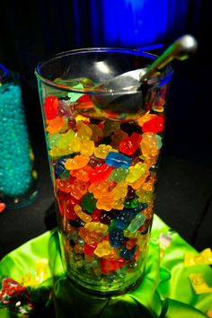 a glass filled with gummy bears sitting on top of a table