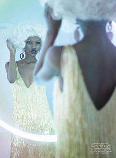 a woman in a yellow dress is looking at herself in the mirror with her hand on her hip