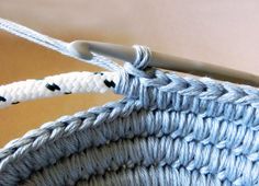 a crochet hook is hanging from the end of a piece of blue yarn