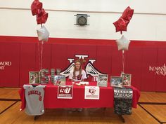 a woman sitting at a table with red and white balloons