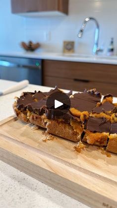 a wooden cutting board topped with lots of food on top of a kitchen counter next to a sink