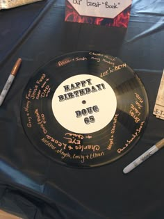 a record with writing on it sitting on a table next to pens and paper tags