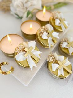 four candles with bows on them sitting next to some flowers and other things in the background