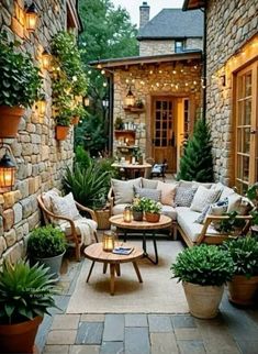 an outdoor living area with couches, tables and potted plants