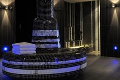 a black and white tiled bathtub with blue lights on the side, in a bathroom