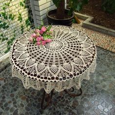 a white doily table with pink flowers on it