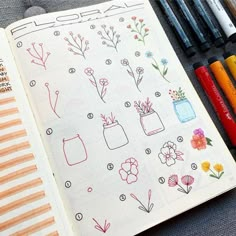 an open notebook with flowers and vases drawn on it next to crayons