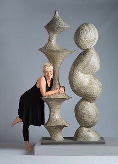 a woman standing next to a tall sculpture