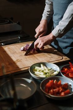 a man cutting up vegetables on top of a wooden cutting board