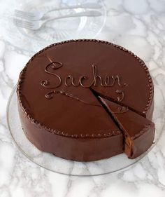 a chocolate cake with the word sacher cut in half on a marble table top