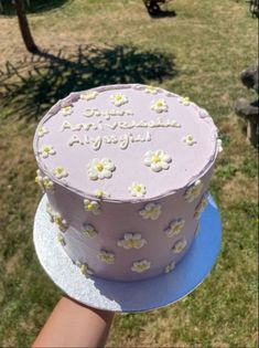 a pink cake sitting on top of a blue plate in front of a grass covered field