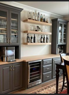 a kitchen with gray cabinets and wine glasses on the shelves