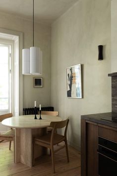 a dining room table and chairs in front of a window with a painting on the wall